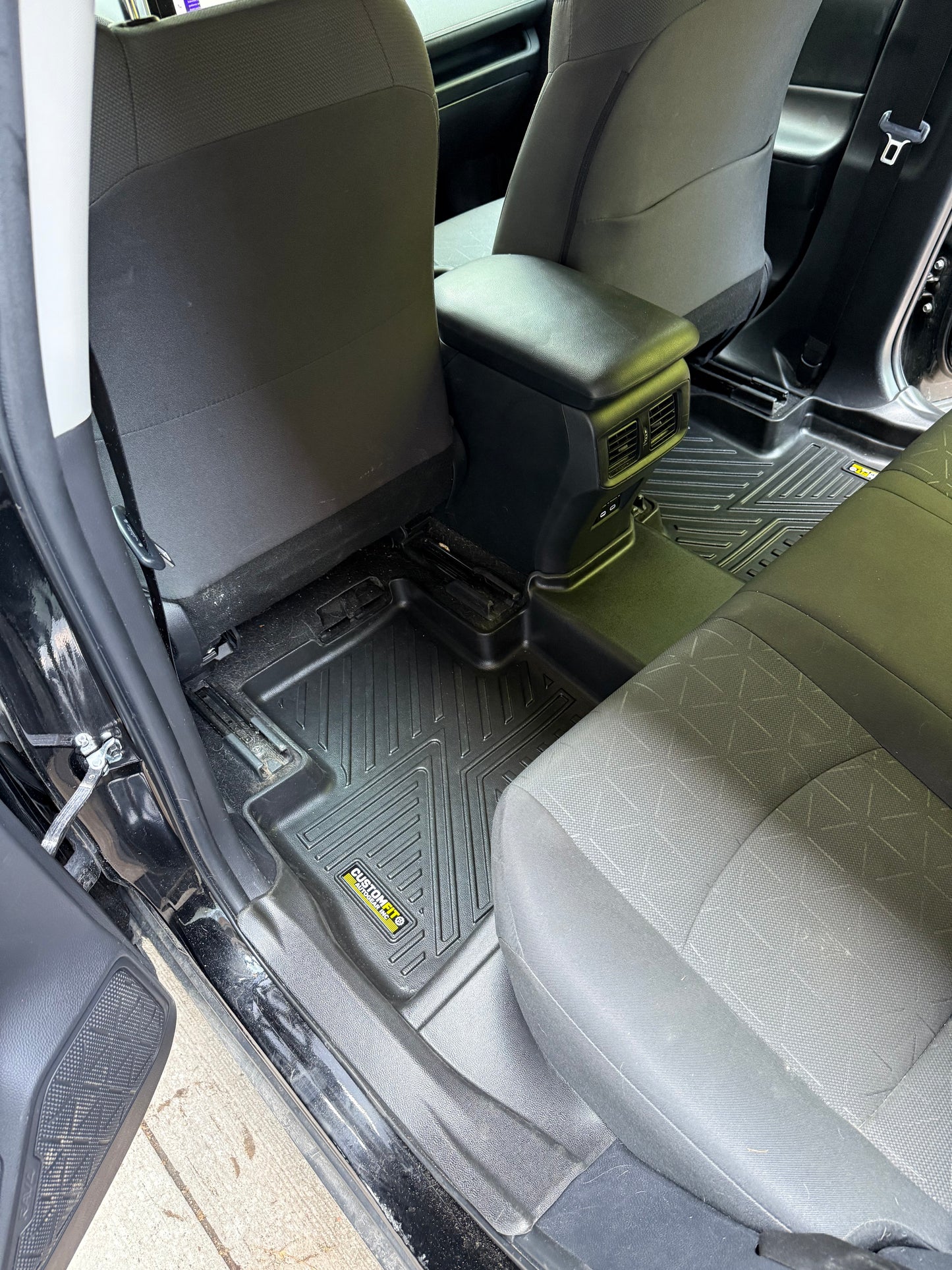 Car interior with gray seats and a black floor mat on a concrete floor.