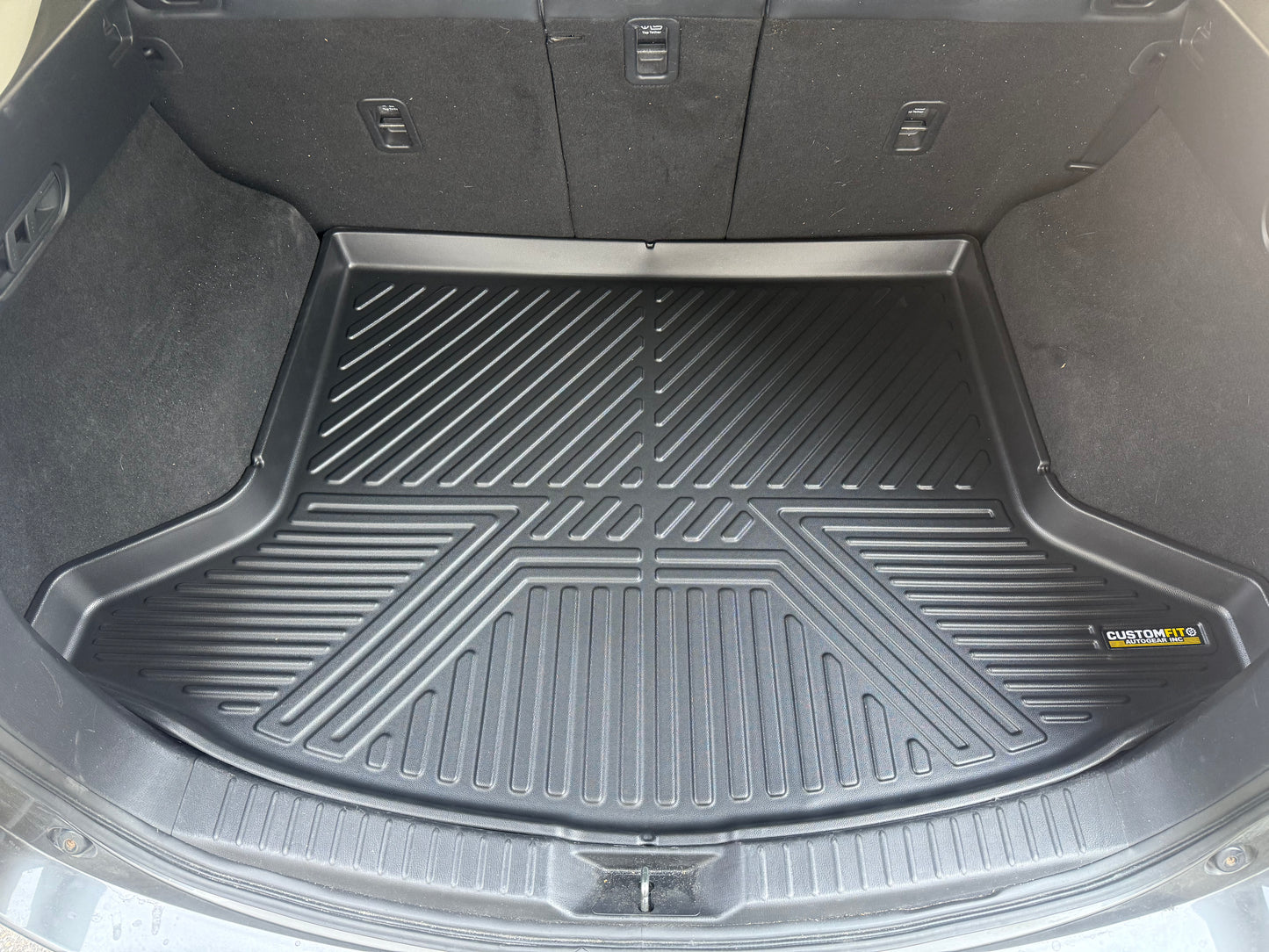 Car trunk with a black cargo liner and a visible brand logo.